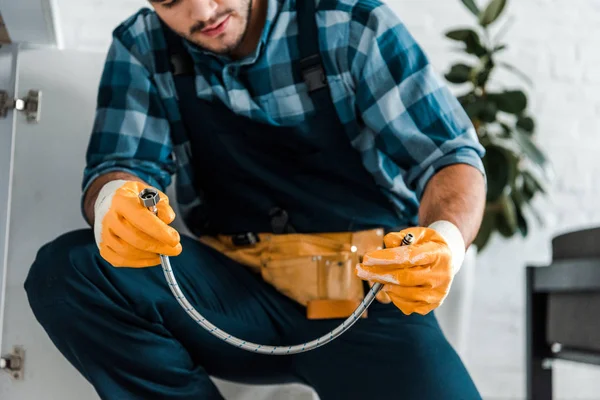 Cropped view of bearded repairman holding metal hose — Stock Photo