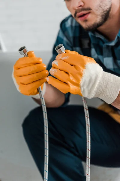 Foco seletivo de reparador barbudo segurando mangueira de metal — Fotografia de Stock