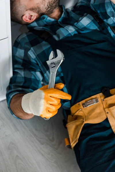 Abgeschnittene Ansicht eines bärtigen Arbeiters, der während der Arbeit in der Küche einen verstellbaren Schraubenschlüssel hält — Stockfoto