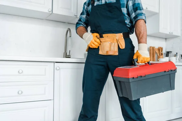 Vue recadrée du bricoleur en uniforme debout et tenant la boîte à outils — Photo de stock