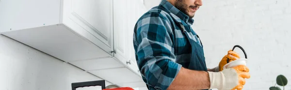 Tiro panorâmico de reparador segurando funil na cozinha — Fotografia de Stock