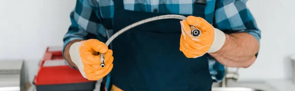 Tiro panorâmico de reparador em luvas de borracha segurando mangueira de metal — Fotografia de Stock