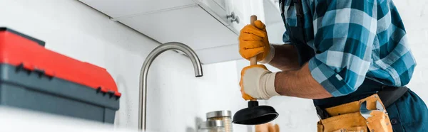 Panoramic shot of repairman holding plunger in kitchen — Stock Photo