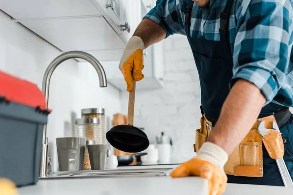 Vista cortada do reparador segurando êmbolo na cozinha — Fotografia de Stock