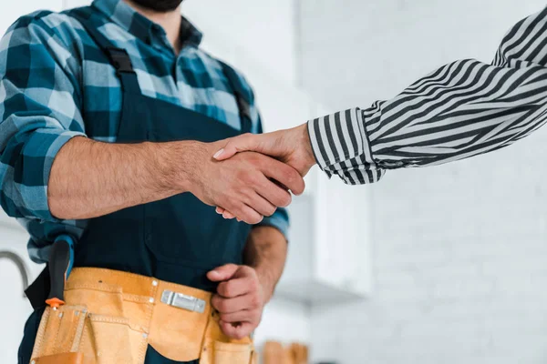 Cropped view of woman shaking hands with handyman — Stock Photo