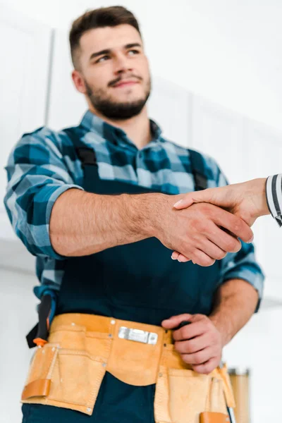 Enfoque selectivo de la mujer estrechando la mano con handyman - foto de stock