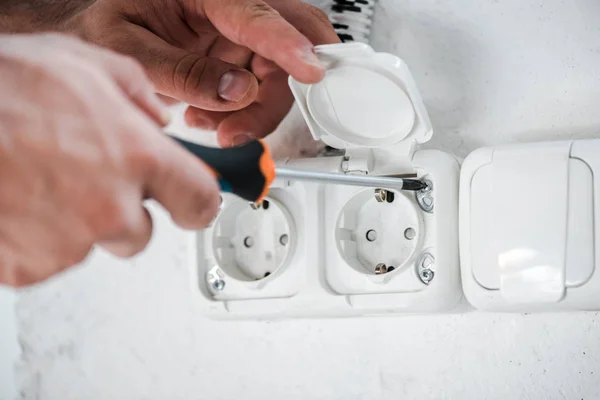 Selective focus of technician holding screwdriver near power socket — Stock Photo