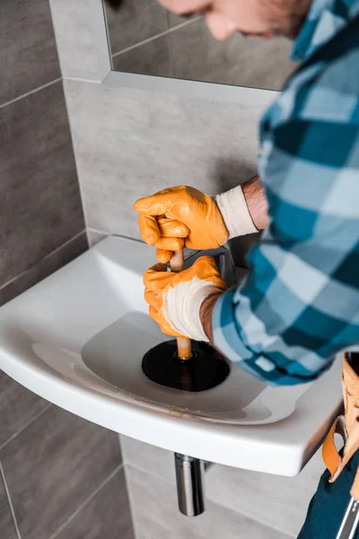 Enfoque selectivo del manitas que sostiene el émbolo en el fregadero con agua - foto de stock