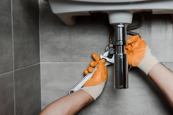 Ausgeschnittene Ansicht eines Reparateurs zur Behebung eines Wasserschadens mit verstellbarem Schraubenschlüssel — Stockfoto