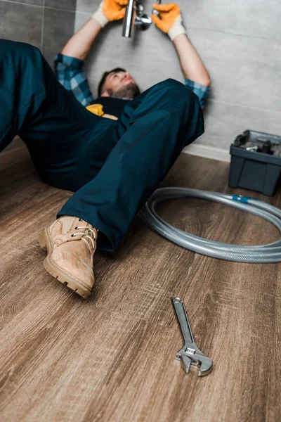 Selective focus of bearded repairman fixing water damage in sink — Stock Photo