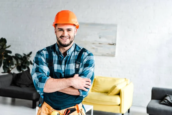 Happy handyman looking at camera while standing with crossed arms — Stock Photo