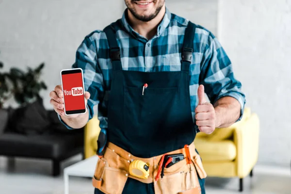 KYIV, UKRAINE - JULY 31, 2019: cropped view of happy man holding smartphone with youtube app on screen and showing thumb up — Stock Photo