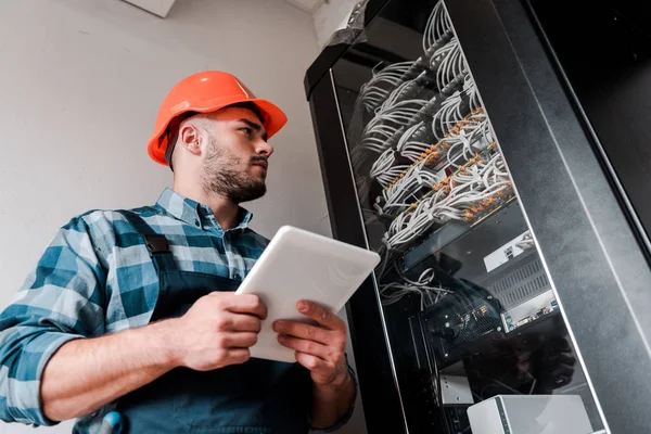 Low angle view of handsome bearded workman using digital tablet — Stock Photo