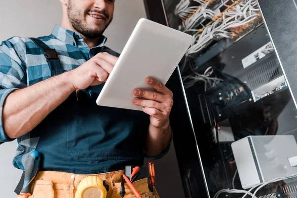 Vue recadrée du technicien barbu heureux en utilisant une tablette numérique — Photo de stock