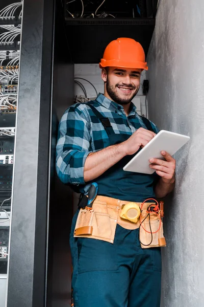 Happy bearded technician in safety helmet using digital tablet — Stock Photo