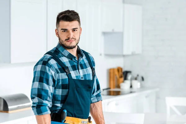 Handsome bearded handyman in uniform looking at camera — Stock Photo