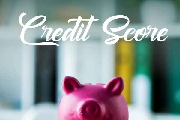 Pink piggy bank on wooden desk near credit score lettering in office — Stock Photo