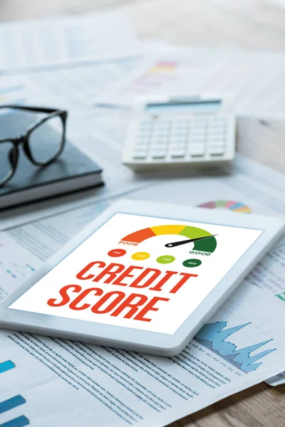 Selektive Fokussierung des digitalen Tablets mit Credit Score Schriftzug in der Nähe von Notizbuch und Brille auf Dokumenten — Stockfoto