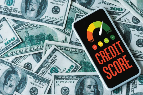 Top view of smartphone with credit score letters on screen on dollar banknotes — Stock Photo