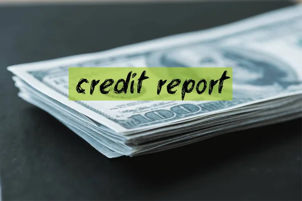 Selective focus of stack with dollar banknotes near credit report lettering on black — Stock Photo