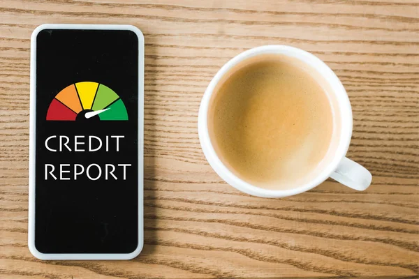 Vue du haut du smartphone avec lettrage de rapport de crédit à l'écran près de tasse de café sur la table — Stock Photo