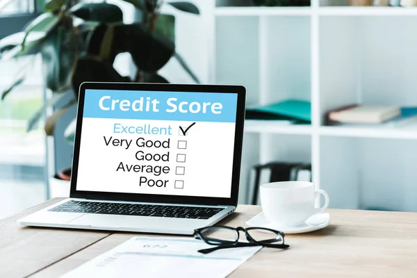 Cup of coffee near laptop with credit score lettering on screen — Stock Photo