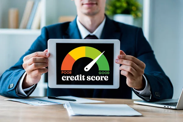 Selective focus of happy man holding digital tablet with credit score lettering in office — Stock Photo
