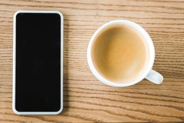 Vue du haut du smartphone avec écran vierge près de tasse de café sur la table — Photo de stock