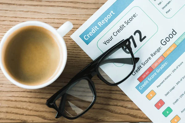 Vue du dessus de la tasse avec café près du papier avec des lettres de crédit sur le papier et des verres sur la table — Photo de stock