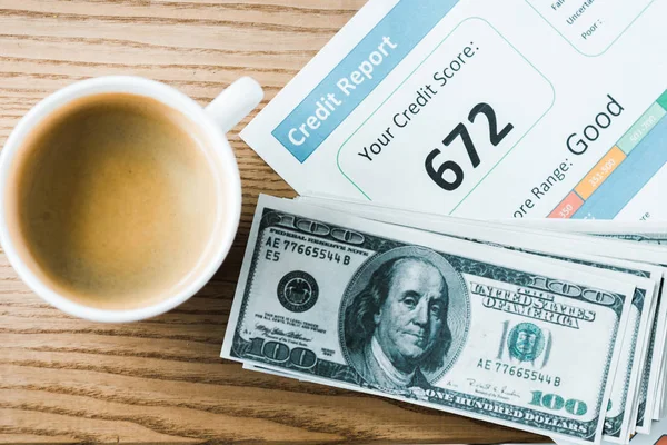 Vista superior de xícara com café perto de papel com letras de relatório de crédito em papel e notas de dólar — Fotografia de Stock