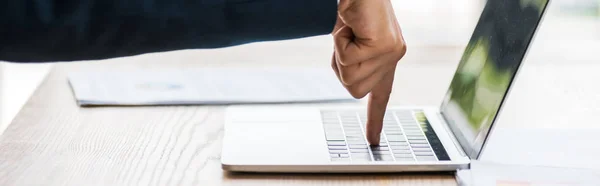 Plano panorámico del hombre apuntando con el dedo al teclado del ordenador portátil - foto de stock