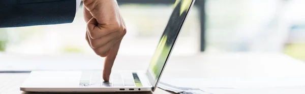 Panoramic shot of businessman pointing with finger at laptop keyboard — Stock Photo