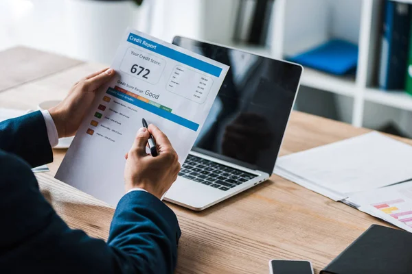 Cropped view of man holding pen near paper with credit report letters — Stock Photo