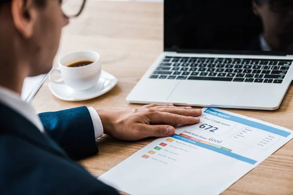 Selective focus of man near paper with credit report letters and cup of coffee — Stock Photo