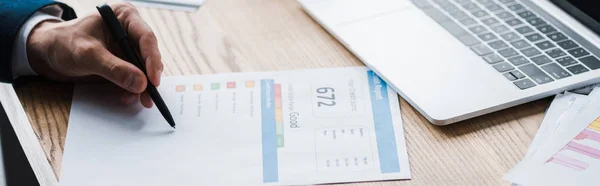 Panoramic shot of man holding pen near paper with credit report letters near laptop — Stock Photo