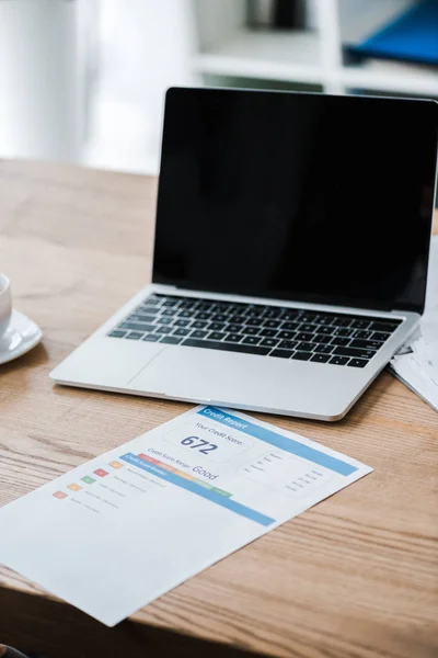 Ordinateur portable avec écran blanc près du papier avec lettrage de rapport de crédit sur le bureau — Stock Photo