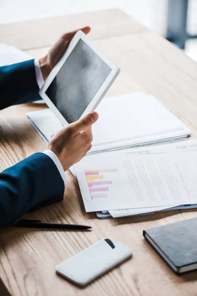 Ausgeschnittene Ansicht des Mannes mit digitalem Tablet und leerem Bildschirm in der Nähe von Diagrammen und Diagrammen auf dem Schreibtisch — Stockfoto