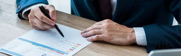 Panoramic shot of man holding pen near paper with lettering on table — Stock Photo