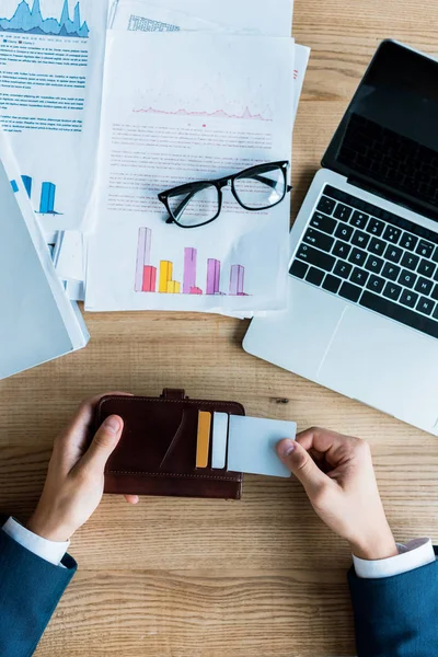 Top view of man holding wallet with credit cards near laptop — Stock Photo