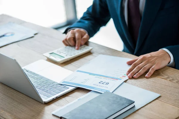 Selective focus of man holding paper with credit report lettering and counting on calculator — Stock Photo