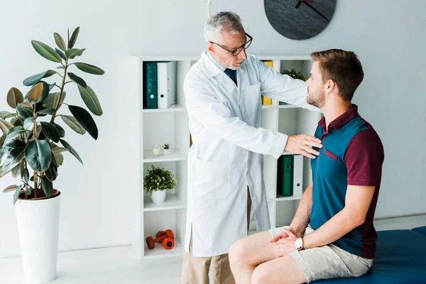 Doctor in glasses and white coat touching patient in clinic — Stock Photo