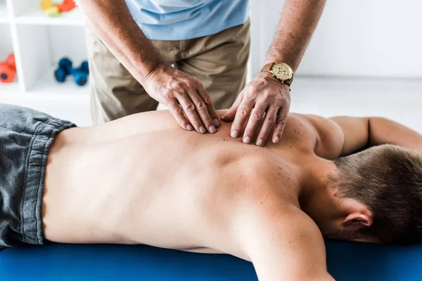 Geschnittene Ansicht eines Chiropraktikers, der dem Mann auf dem Massagetisch massiert — Stockfoto