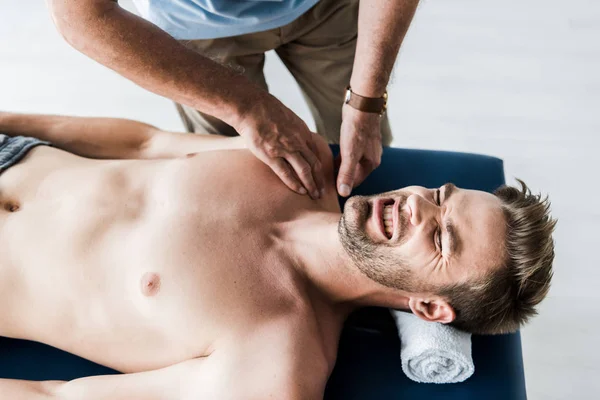 Vista aérea del quiropráctico haciendo masaje al hombre con dolor - foto de stock
