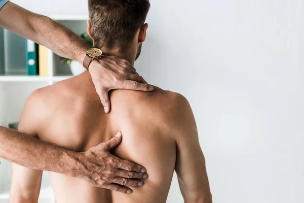 Ausgeschnittene Ansicht des Arztes, der den Rücken des hemdlosen Patienten berührt — Stockfoto