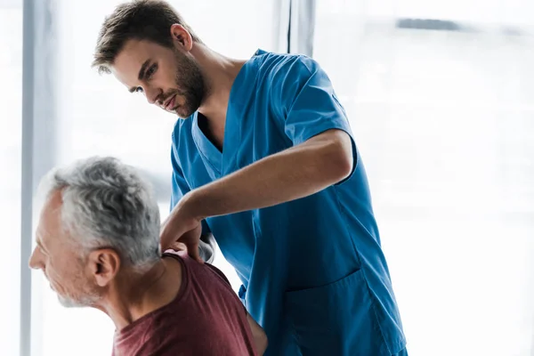 Selective focus of handsome doctor touching shoulder of man — Stock Photo