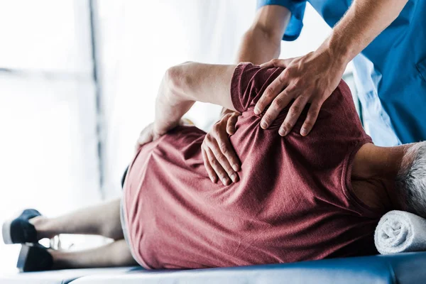 Selektiver Fokus des Arztes, der Patienten mittleren Alters auf Massagetisch berührt — Stockfoto