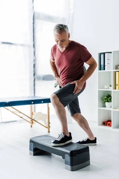 Homem de meia idade se exercitando na plataforma passo na clínica — Fotografia de Stock