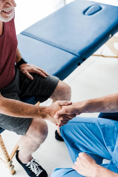 Vista aerea del medico che stringe la mano al paziente allegro — Foto stock