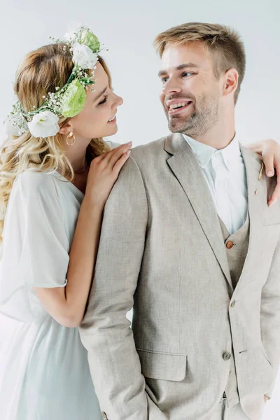 Attraktive Braut und schöner Bräutigam lächeln und schauen einander vereinzelt auf grau an — Stockfoto