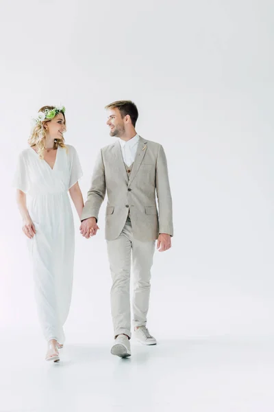 Attractive bride and handsome bridegroom holding hands and looking at each other — Stock Photo